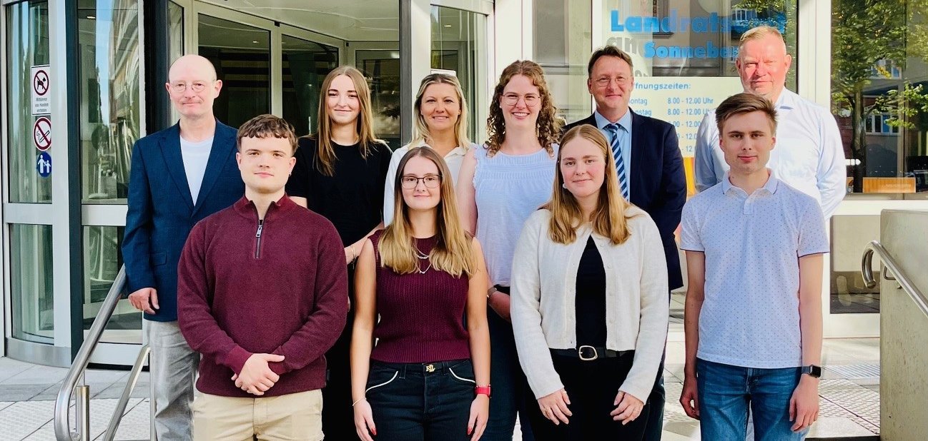 Die Nachwuchskräfte Leonie Graul (hinten 2.v.l.), Pascal Jahn (vorne l.), Emily Sperschneider (vorne 2.v.l.), Vivien Sophie Schwesinger (vorne 2.v.r.) und Tom Unbehaun (vorne r.) mit Landrat Robert Sesselmann (hinten, 2.v.r.), dem Hauptamtlichen Beigeordneten Andreas Groß (hinten, l.), den Ausbildungsleiterinnen Carolin Engelbrecht (hinten 3.v.l.) und Josefine Weidenhammer (hinten 3.v.r.) sowie Personalamtsleiter Steffen Zinner (hinten r.)