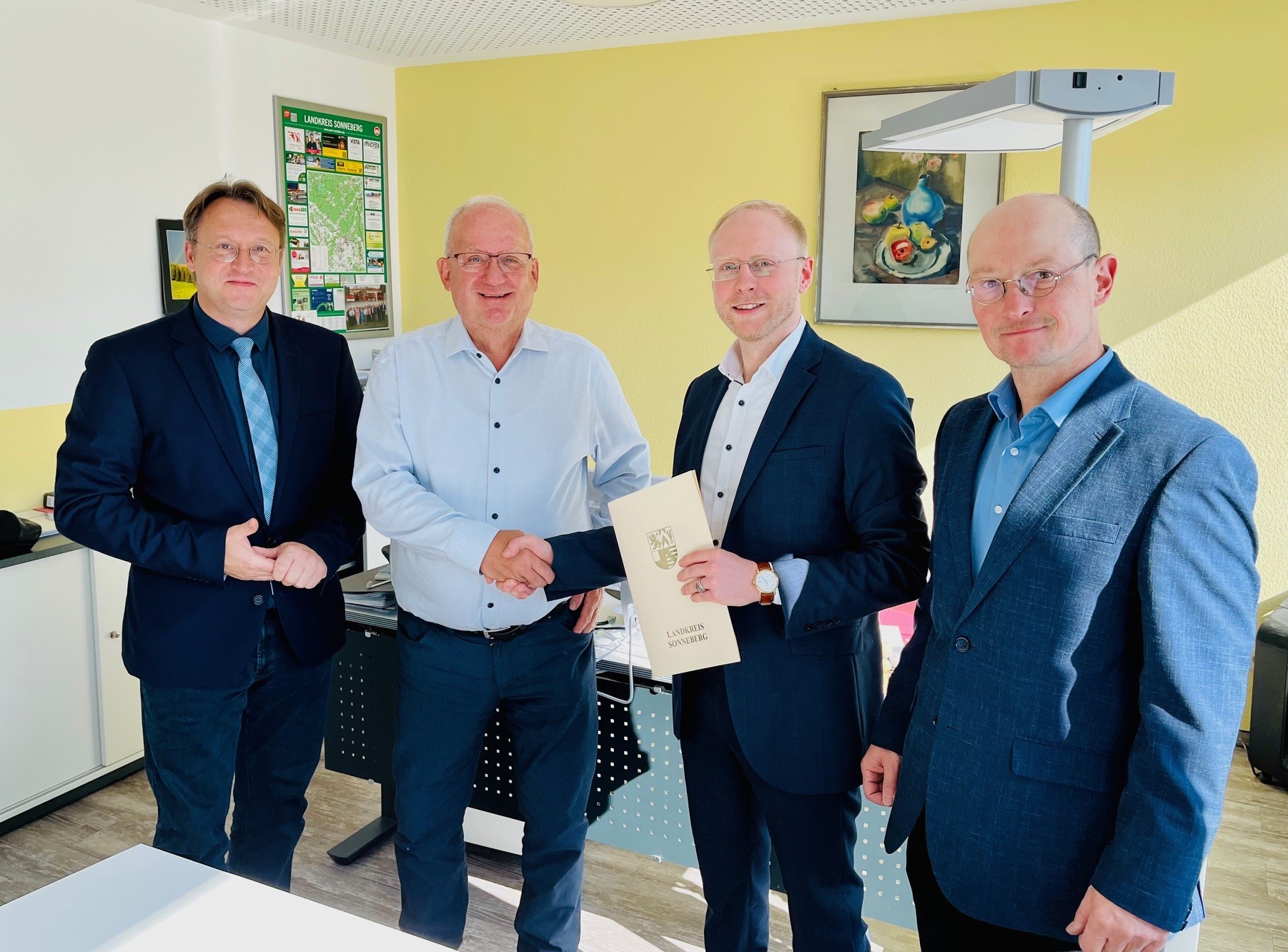 Handschlag zwischen dem scheidenden OVG-Geschäftsführer Klaus Dieter Schneider (2.v.l.) und seinem Nachfolger Matthias Böhm (2.v.r.) im Beisein von Landrat Robert Sesselmann (l.) und dem Hauptamtlichen Beigeordneten Andreas Groß