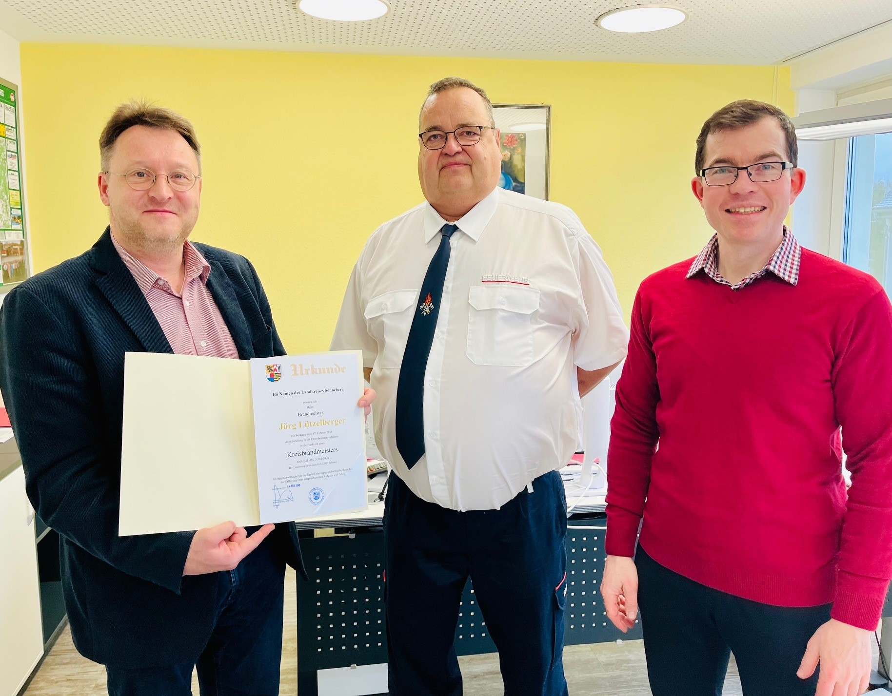 Übergabe der Ernennungsurkunde zum Kreisbrandmeister an Jörg Lützelberger (M.) durch Landrat Robert Sesselmann (l.) im Beisein von Kreisbrandinspektor Mathias Nüchterlein (r.)
